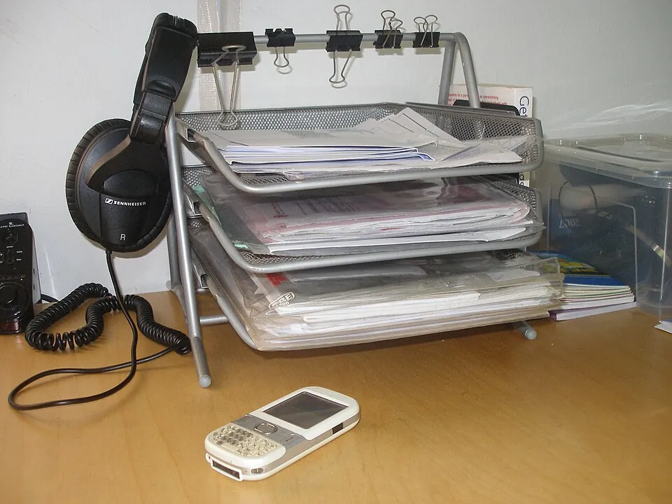 机の上のヘッドホンと、書類が積み重なったトレー